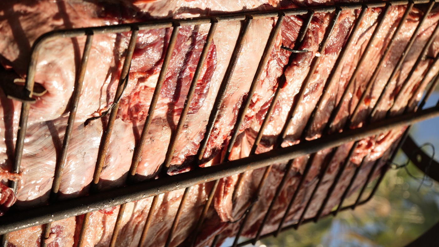 Beef ribs slow-cooking on the cross over the fire
